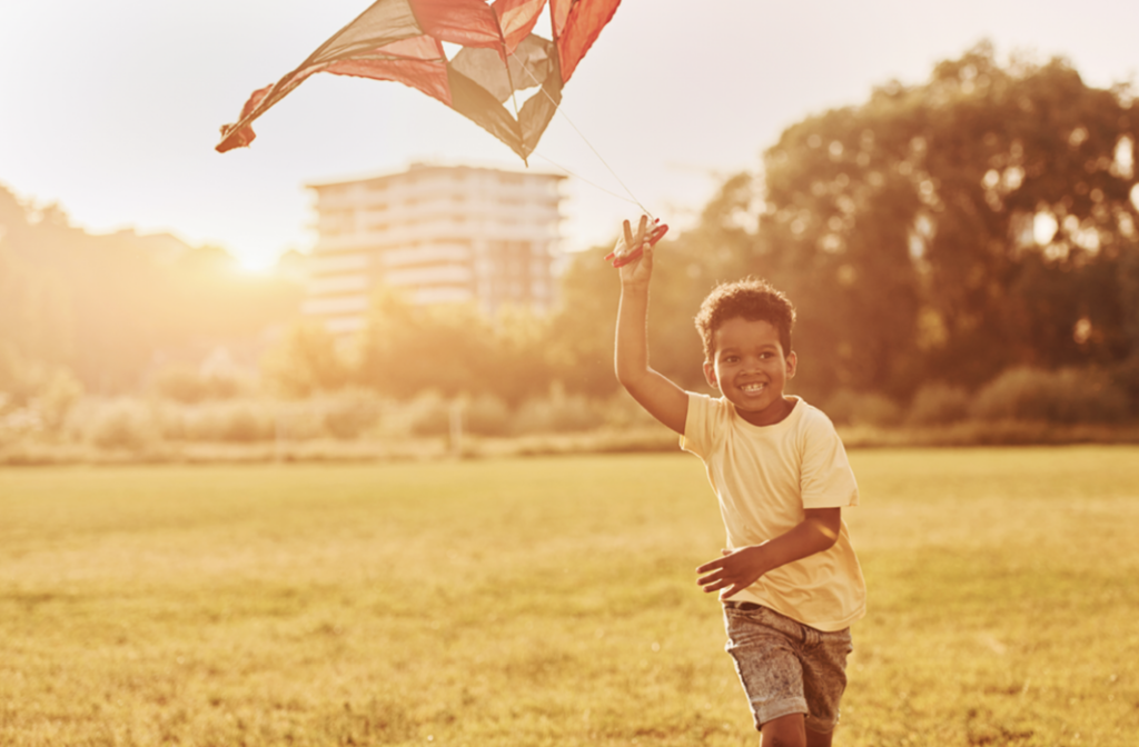 Young boy running through a field with a kite